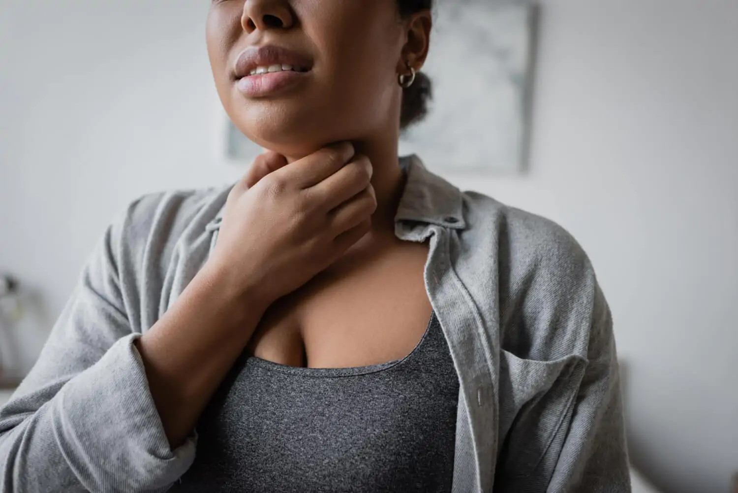 Mulher com a mão no pescoço sentindo desconforto na garganta e sintomas de irritação