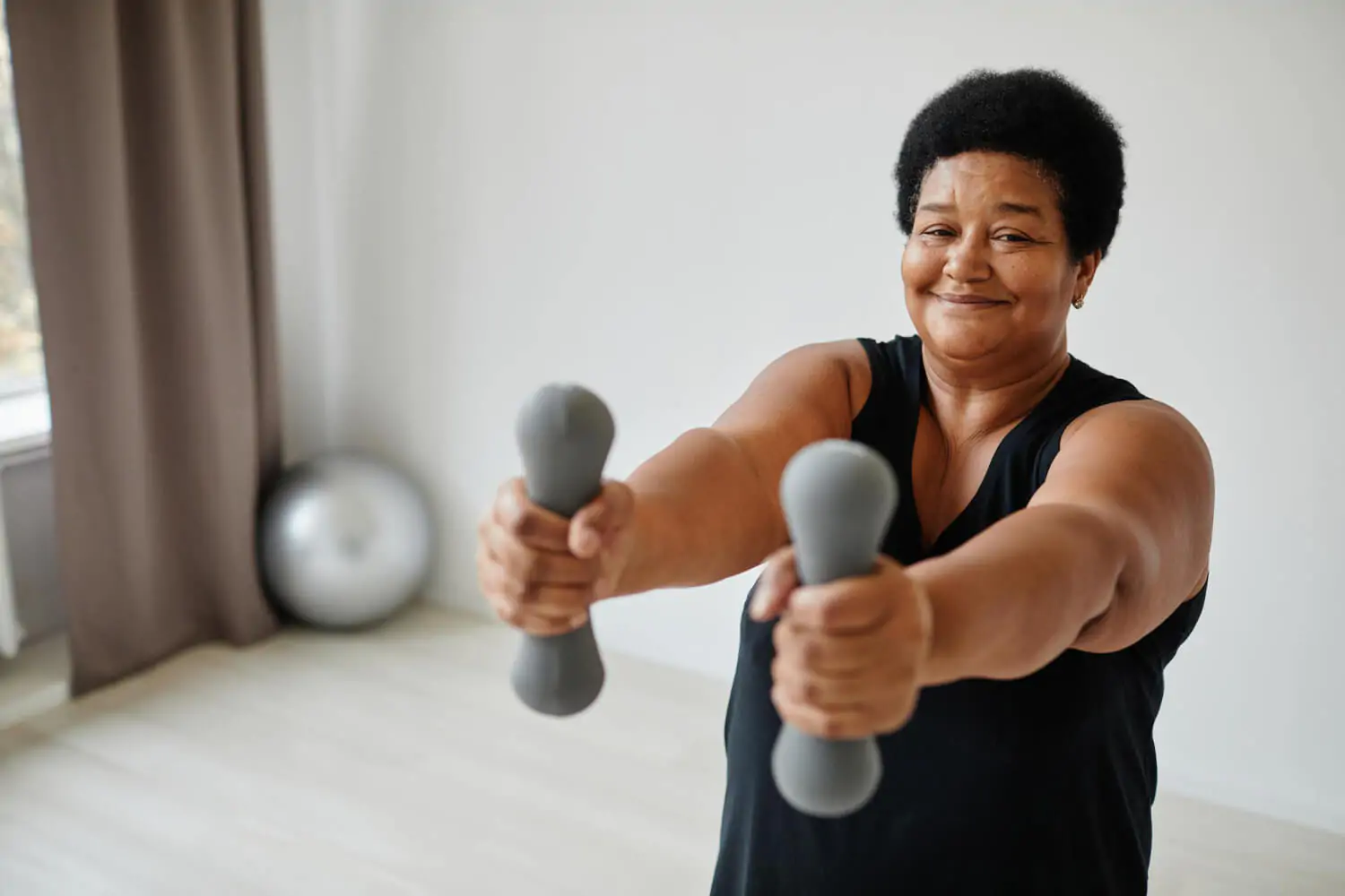 Mulher realizando exercício com halteres para fortalecer músculos e preservar a saúde das articulações.